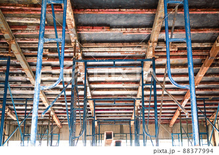 Setting up steel scaffolding to support floors for concrete work on tall buildings. A view up under the floor to support the concrete floor. Setting up a concrete pouring form on the second floor. Setting up steel scaffolding to support floors for concrete work on tall buildings. A view up under the floor to support the concrete floor. Setting up a concrete pouring form on the second floor. 88377994