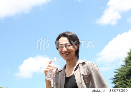 ミネラルウォーターを飲む笑顔の若い男性 88378090
