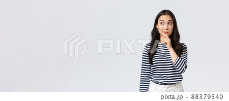 Lifestyle, beauty and fashion, people emotions concept. Thoughtful young asian girl searching for solution, thinking looking away and touching chin while pondering decision 88379340