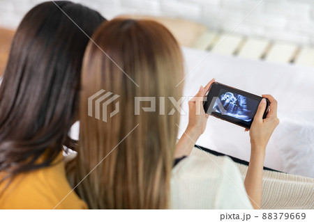 The LGBT couple is planning to have their babies. They looking toward on the future together. They looking at the ultrasound of the children on their screen ad also happy together. The LGBT couple is planning to have their babies. They looking toward on the future together. They looking at the ultrasound of the children on their screen ad also happy together. 88379669