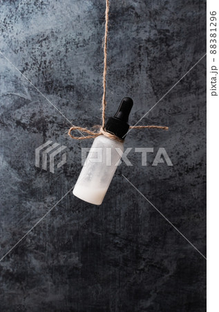 Bottle of cosmetic product on dark background. Vertical photo, poster. Copy space. Concept of organic, zero waste cosmetics in reusable container. Facial serum for skin care. Close up. 88381296