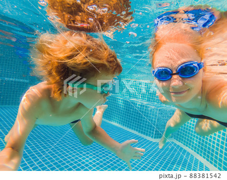 Little boy learning to swim in a swimming pool, mother holding the child Little boy learning to swim in a swimming pool, mother holding the child 88381542