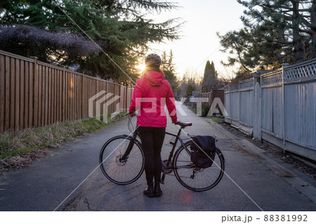 Adventurous Woman Standing with a bicycle at an Alleyway in Modery City Suburbs Adventurous Woman Standing with a bicycle at an Alleyway in Modery City Suburbs 88381992