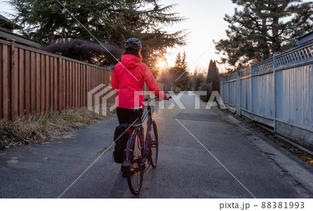 Adventurous Woman Standing with a bicycle at an Alleyway in Modery City Suburbs Adventurous Woman Standing with a bicycle at an Alleyway in Modery City Suburbs 88381993