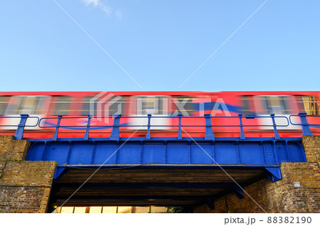 A red train crossing a blue bridge with motion blur. Large area of clear blue sky for copy space. A red train crossing a blue bridge with motion blur. Large area of clear blue sky for copy space. 88382190