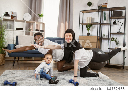 Young family african man and muslim arabic woman practising yoga stretching workout at home Young family african man and muslim arabic woman practising yoga stretching workout at home 88382423