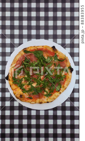 Prosciuto e arugula pizza on black and white squares background 88383955