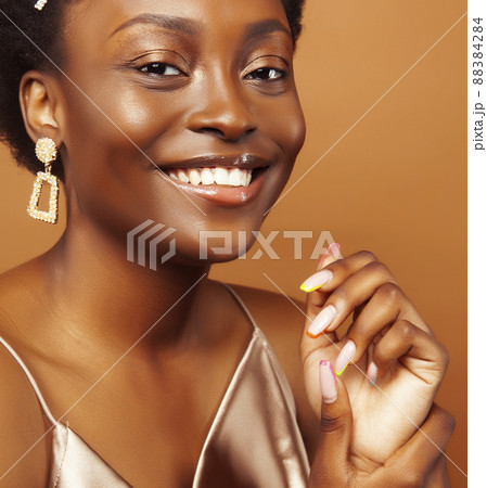 pretty young african american woman with curly hair posing cheerful gesturing on brown background, lifestyle people concept 88384284