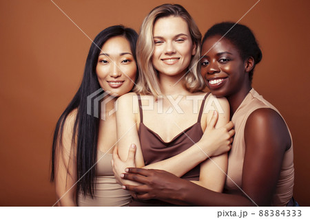 young pretty asian, caucasian, african woman posing cheerful together on brown background, lifestyle diverse nationality people concept young pretty asian, caucasian, african woman posing cheerful together on brown background, lifestyle diverse nationality people concept 88384333
