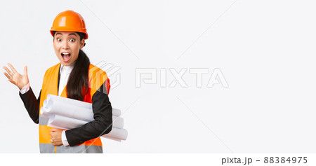 Impressed and fascinated asian female engineer, lead architect at construction area, pointing behind at something awesome, carry blueprint of project, wearing safety helmet and reflective jacket Impressed and fascinated asian female engineer, lead architect at construction area, pointing behind at something awesome, carry blueprint of project, wearing safety helmet and reflective jacket 88384975