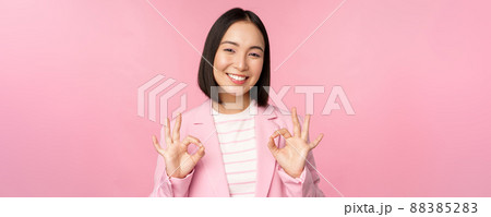 Okay, excellent. Businesswoman in corporate suit, showing ok, approval gesture, recommending smth, give positive feedback and smiling pleased, posing over pink background Okay, excellent. Businesswoman in corporate suit, showing ok, approval gesture, recommending smth, give positive feedback and smiling pleased, posing over pink background 88385283