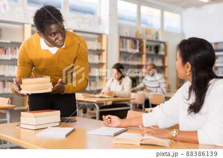 Portrait of librarian handing book to woman Portrait of librarian handing book to woman 88386139