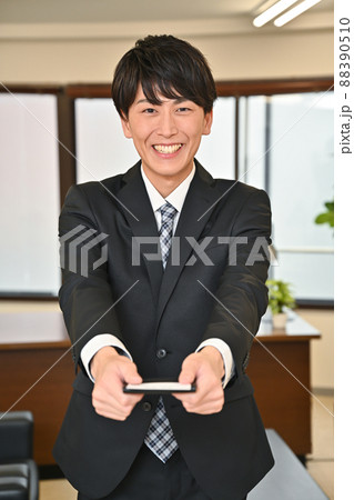 笑顔で名刺を差し出す男性 88390510