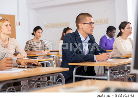 Intelligent adult man in glasses listening to lecture in classroom 88391242