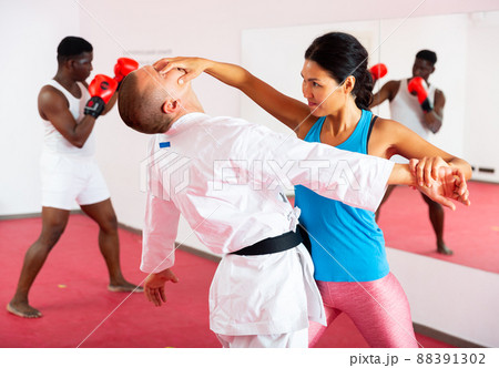 Woman exercising with trainer and man boxing in gym 88391302