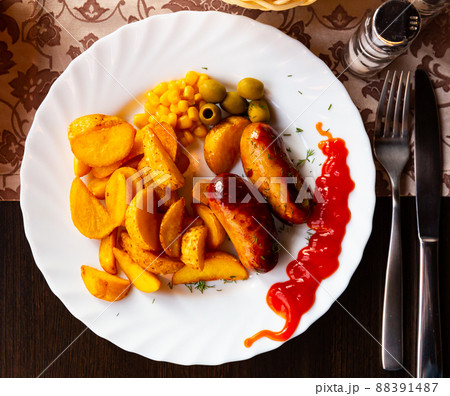 Grilled sausages served with potatoes, olives and chili sauce 88391487