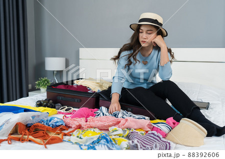 stressed woman having problem with packing a suitcase on bed at home, holiday travel concept stressed woman having problem with packing a suitcase on bed at home, holiday travel concept 88392606