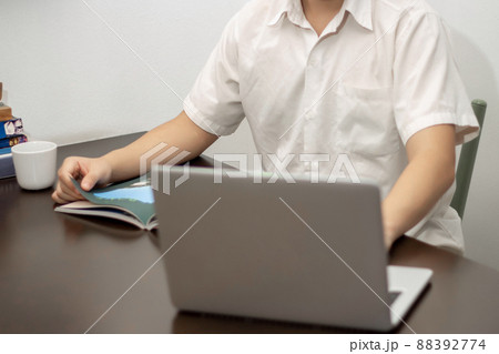 Remote work concept, Male freelancer reading business news on a book and working on laptop at home Remote work concept, Male freelancer reading business news on a book and working on laptop at home 88392774