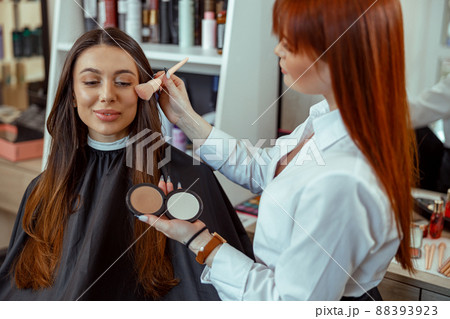 Professional makeup artist applying bronzer powder with a brush in beauty salon Professional makeup artist applying bronzer powder with a brush in beauty salon 88393923