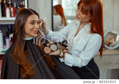 Professional makeup artist doing makeup with a brush in beauty salon 88393924