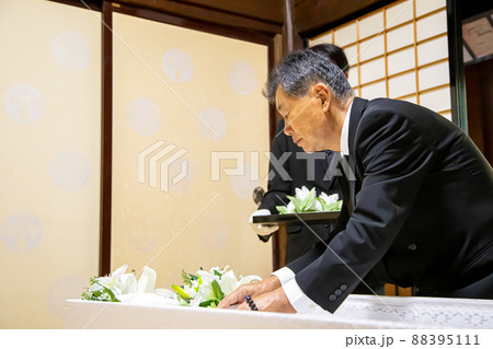 お葬式の納棺式で花入れの儀をする高齢者男性 お葬式の納棺式で花入れの儀をする高齢者男性 88395111