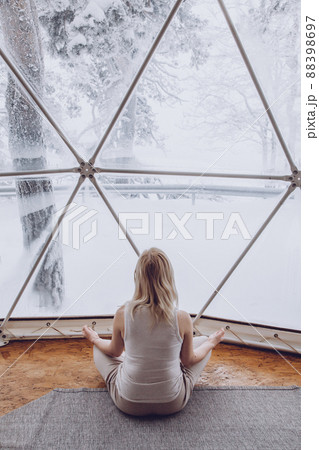 A woman sits in a geo dome glamping tent and meditates, does pranayamas, looks at the winter snow-covered nature. A woman sits in a geo dome glamping tent and meditates, does pranayamas, looks at the winter snow-covered nature. 88398697