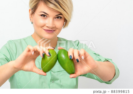 Female nutritionist doctor wearing green workwear holding green organic avocado fruit. Healthy lifestyle concept Female nutritionist doctor wearing green workwear holding green organic avocado fruit. Healthy lifestyle concept 88399815