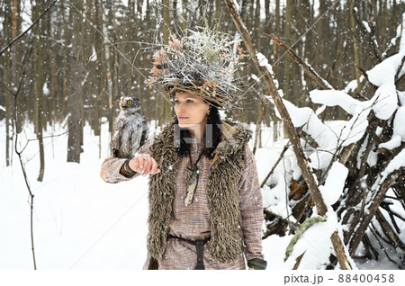 Beautiful woman with a owl on her hand in the winter forest 88400458