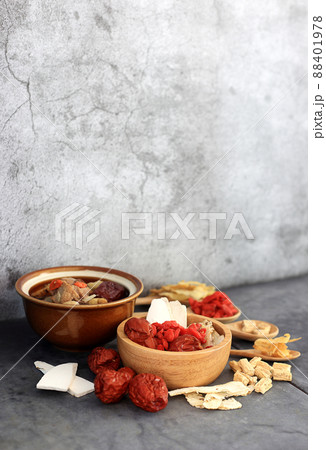 Chinese food - Clear soup with chinese herbal medicine on black background against gray wall Chinese food - Clear soup with chinese herbal medicine on black background against gray wall 88401978