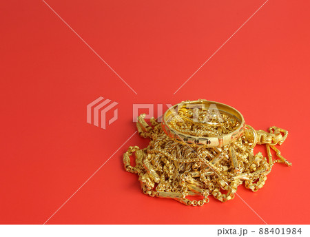 Many gold jewelry - shiny necklace and bracelet on red background with space 88401984
