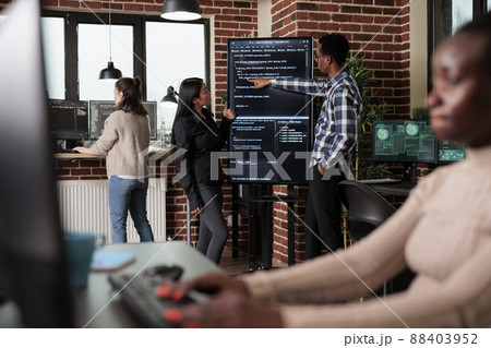 African american back end network developer explaining to coworker application lines of code. Team developing additional layers of security in order to sustain good functionality of system. African american back end network developer explaining to coworker application lines of code. Team developing additional layers of security in order to sustain good functionality of system. 88403952
