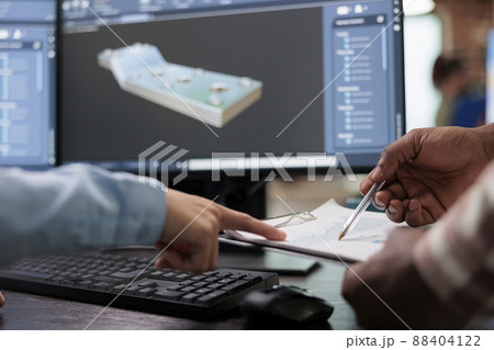 Close up of creative industry employees with clipboard and advanced 3D modeling software open in background. 3D digital artists reviewing sketch scene plan and simulated render times, 88404122