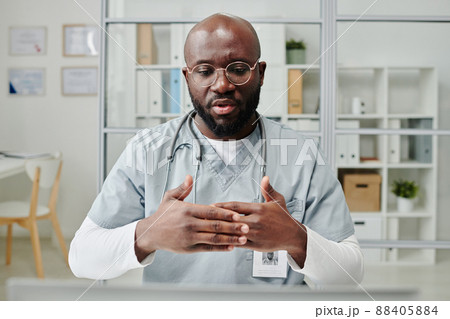 Young confident physician in eyeglasses and uniform consulting online patient Young confident physician in eyeglasses and uniform consulting online patient 88405884