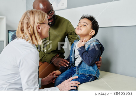 Sick little boy complaining on sore throat to mature female peditrician Sick little boy complaining on sore throat to mature female peditrician 88405953