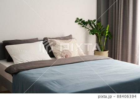Comfortable double bed with group of soft cushions and blue blanket 88406394