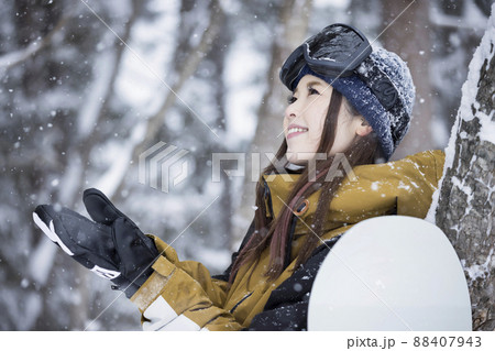 雪の降るスキー場に立つスノボ女子 88407943