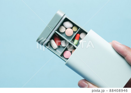 man's hands taking medicine from a pill box  88408946