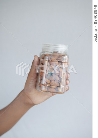 hand holding a jar of almond nuts on white  88408949