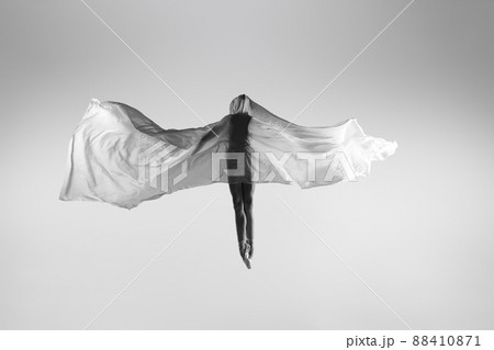 Black and white portrait of graceful ballerina dancing with fabric, cloth isolated on grey studio background. Grace, art, beauty concept. Weightless, flexible. 88410871