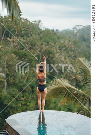 Woman sititng by the swimming pool. Lady in a swimsuit. Girl relaxing by the pool at a beach club in Bali Indonesia 88412291