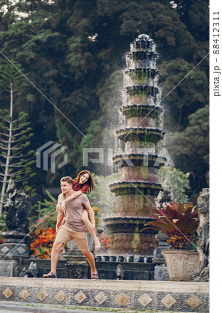 Couple in Bali near a stunning temple. Brunette in a red dress. Couple in Bali near a stunning temple. Brunette in a red dress. 88412311