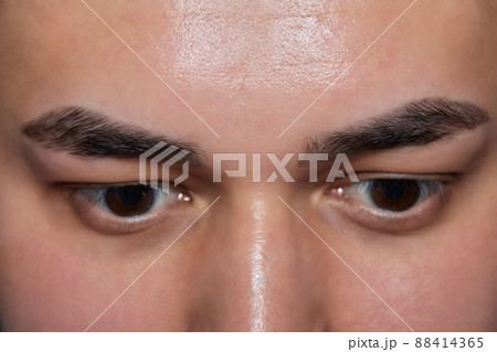 Professional barber doing threading procedure and correcting shape of eyebrows to young male client with tweezer in barber shop. Barber at work. Brow care concept. Plucking brows. Professional barber doing threading procedure and correcting shape of eyebrows to young male client with tweezer in barber shop. Barber at work. Brow care concept. Plucking brows. 88414365