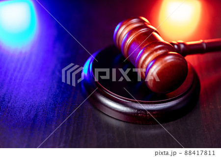 Law theme. Court of law trial in session. Judge gavel on wooden table with police emergency services light. Mallet of judge on dark background. Justice human rights concept 88417811