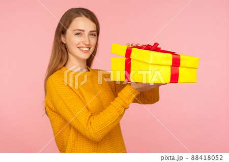 Portrait of attractive red hair girl in sweater opening gift box and smiling at camera, unboxing birthday surprise, satisfied with holiday present. indoor studio shot isolated on pink background 88418052