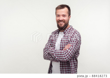Portrait of cheerful good-natured bearded young man in casual plaid shirt crossing arms and smiling sincerely at camera, looking satisfied contented with life. studio shot isolated on white background Portrait of cheerful good-natured bearded young man in casual plaid shirt crossing arms and smiling sincerely at camera, looking satisfied contented with life. studio shot isolated on white background 88418273