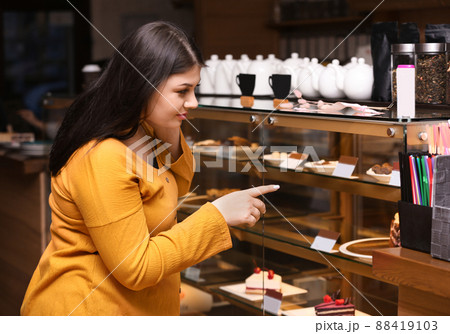 Beautiful overweight woman near pastry shop display. Plus size model Beautiful overweight woman near pastry shop display. Plus size model 88419103