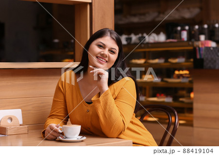 Beautiful overweight woman at table in cafe. Plus size model Beautiful overweight woman at table in cafe. Plus size model 88419104
