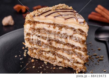 Esterhazy cake sliced on black plate close-up. Delicatessen sweet dessert with almond meringue dough and buttercream 88419473