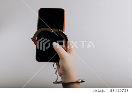 Smartphone chained to handcuff in woman's hand isolated on grey background. Information security or smartphone addiction concept 88419733