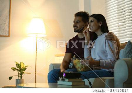 Young couple watching movie using video projector at home. Space for text Young couple watching movie using video projector at home. Space for text 88419814
